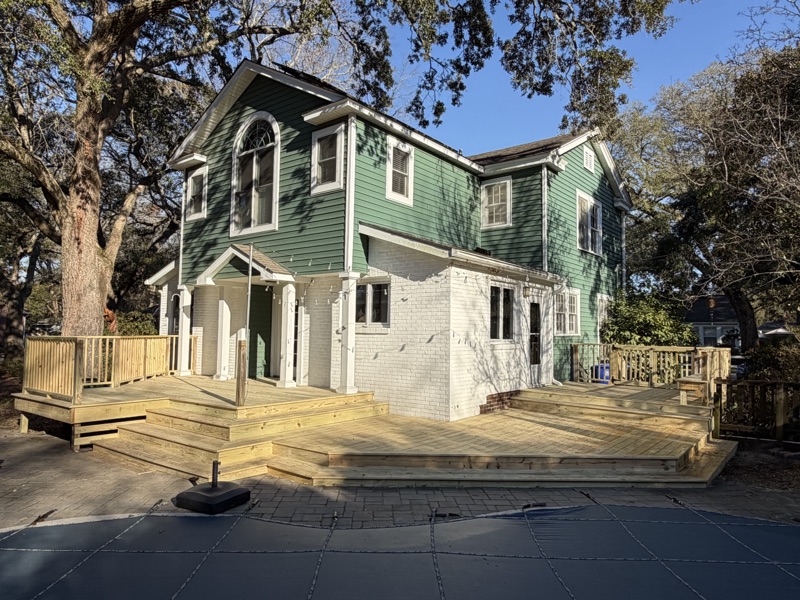 Large custom multi-level wood deck wrapping a Lowcountry home, with a pool in the foreground