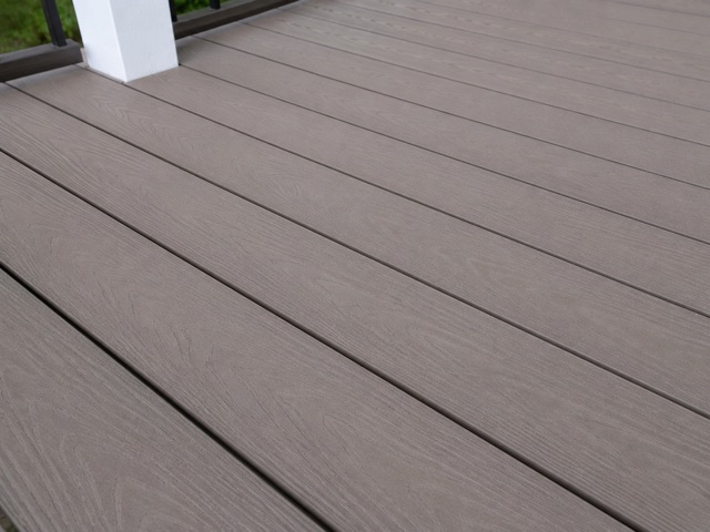 Greige composite deck boards with a low-sheen wood-grain finish